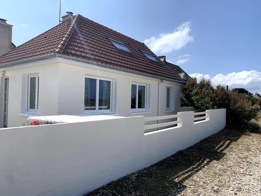 a white house with a fence in front of it at Maison les pieds dans l'eau in Quinéville