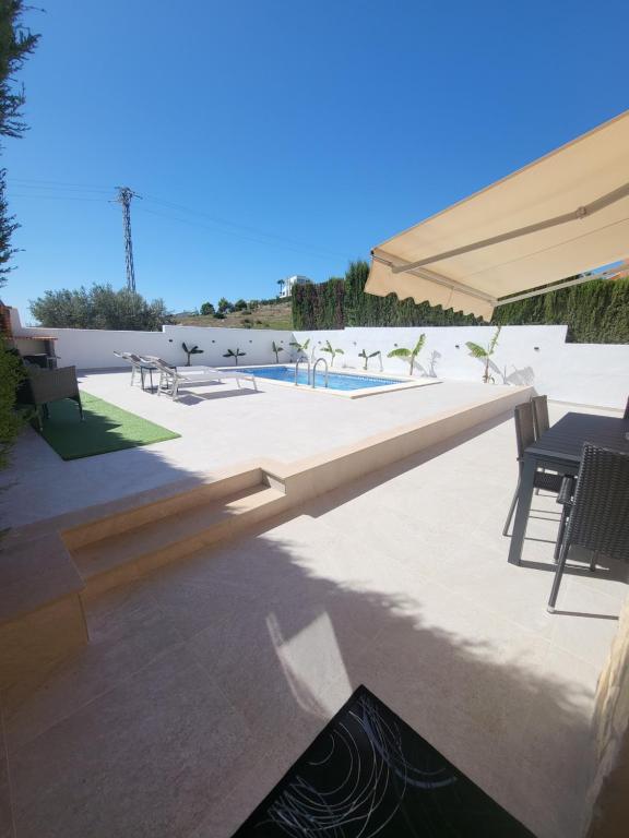 a patio with a pool and a large umbrella at Chalet Edy con piscina in Peniscola