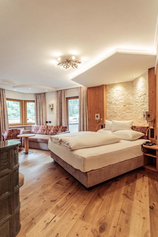 a bedroom with a large bed and a living room at Hotel Neuhintertux in Tux