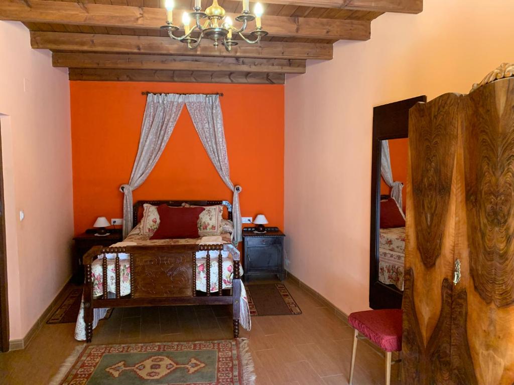 1 dormitorio con paredes de color naranja, 1 cama y espejo en Piedra Dorada, en Pereruela