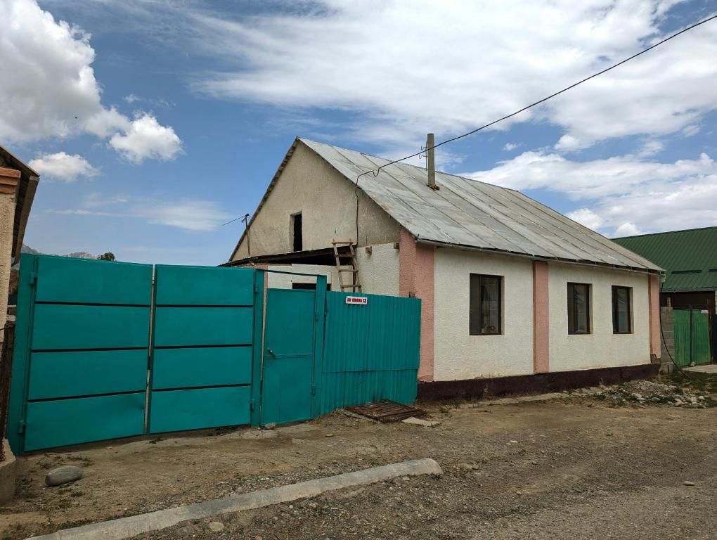 une petite maison avec une clôture bleue devant elle dans l'établissement Baisal Guest House, à Orto-Saz