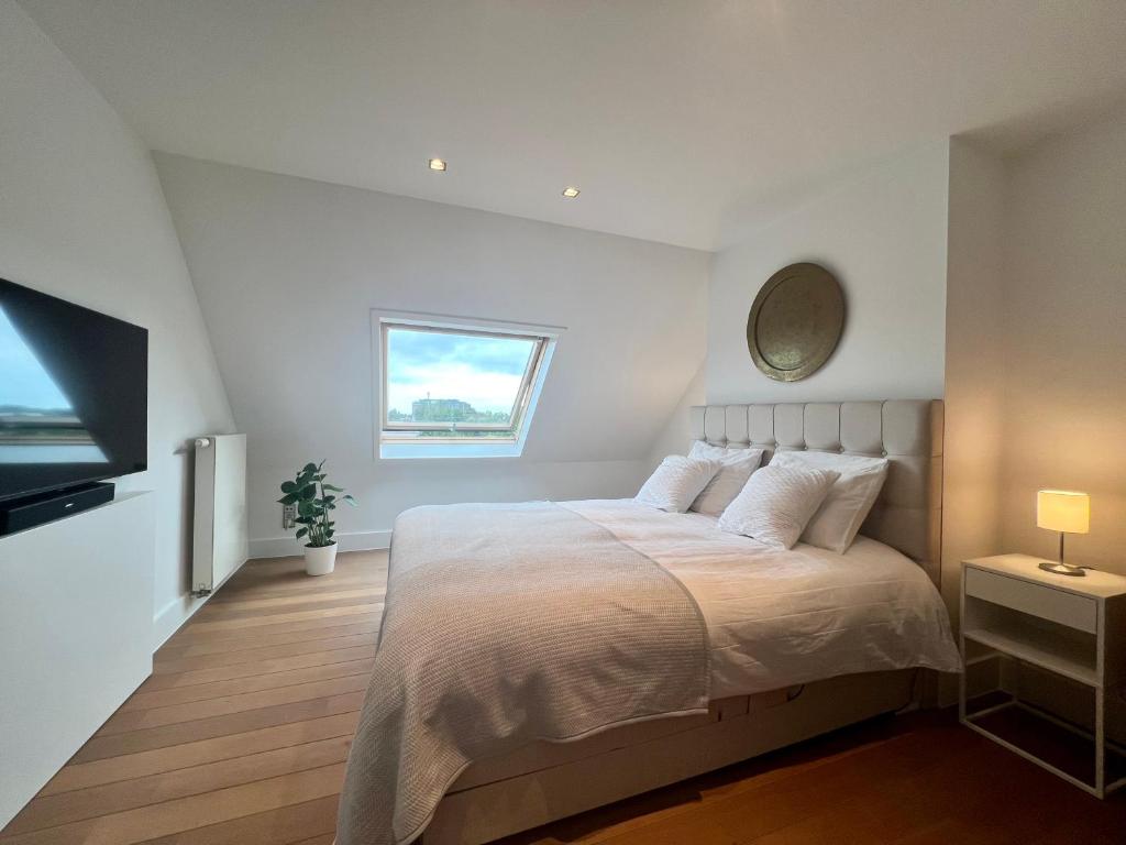 a white bedroom with a bed and a tv at Luxury Business Accommodation Geel in Geel