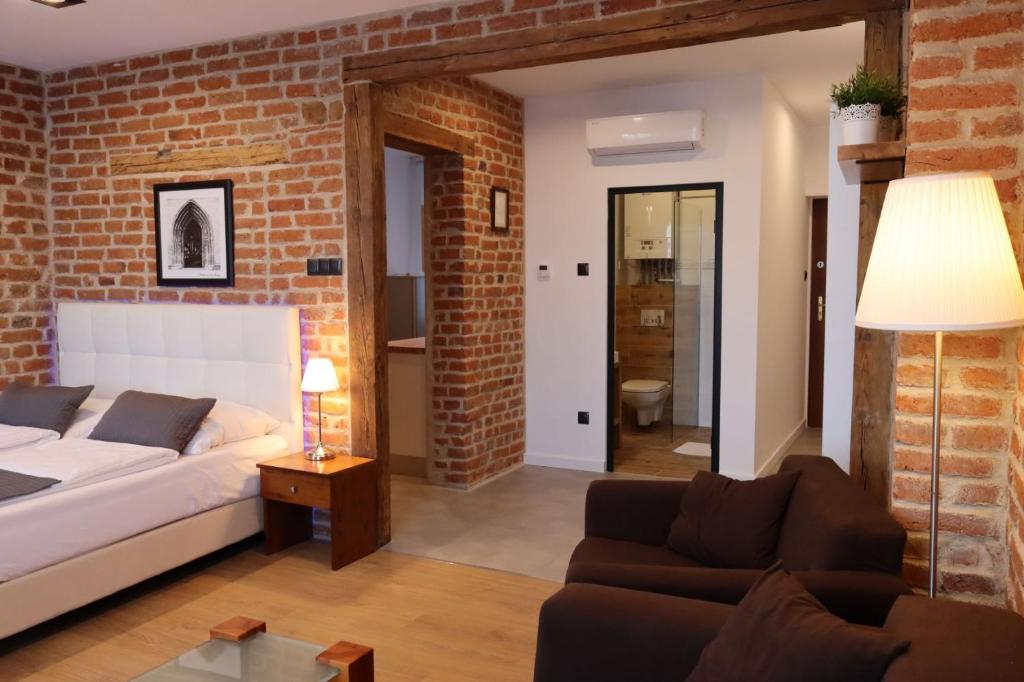 uma sala de estar com paredes de tijolo, uma cama e um sofá em APARTAMENT PRZY RYNKU em Chełmno