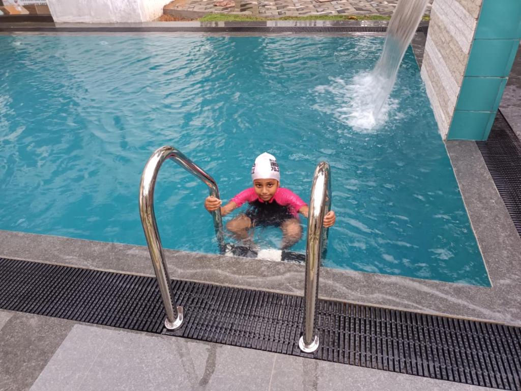 a child in a swimming pool with two metal rails at Viking Villa in Kalagedihena