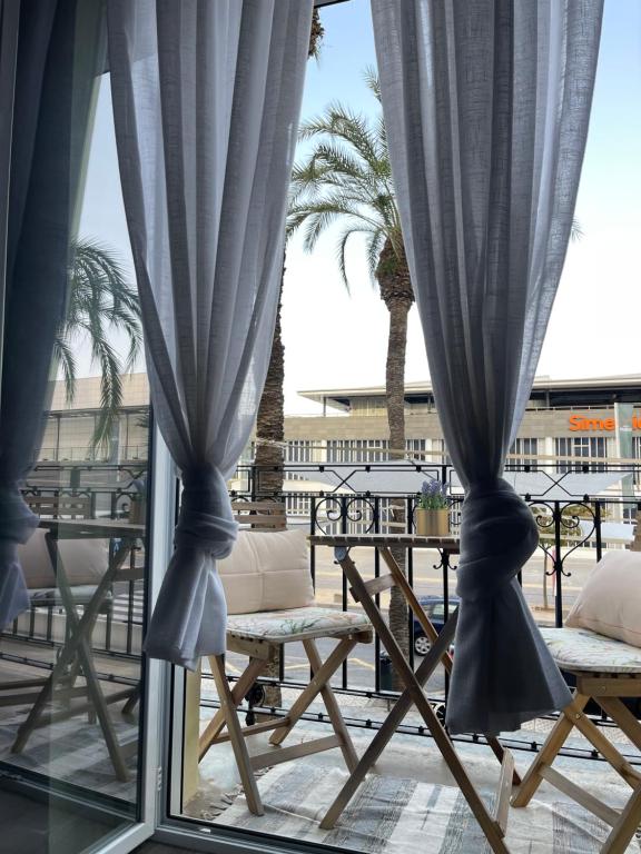 a window with blue curtains and tables and palm trees at Centrally Located Spacious Private Apartment BuenaVista in Grao with Rooftop in Grao de Castellón