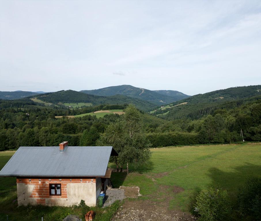 a small house in a field with mountains in the background at Magiczne Wzgórze in Ustroń