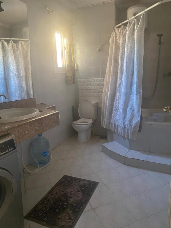 uma casa de banho com uma banheira, um WC e um lavatório. em الساحل الشمالي em Abû Zeira