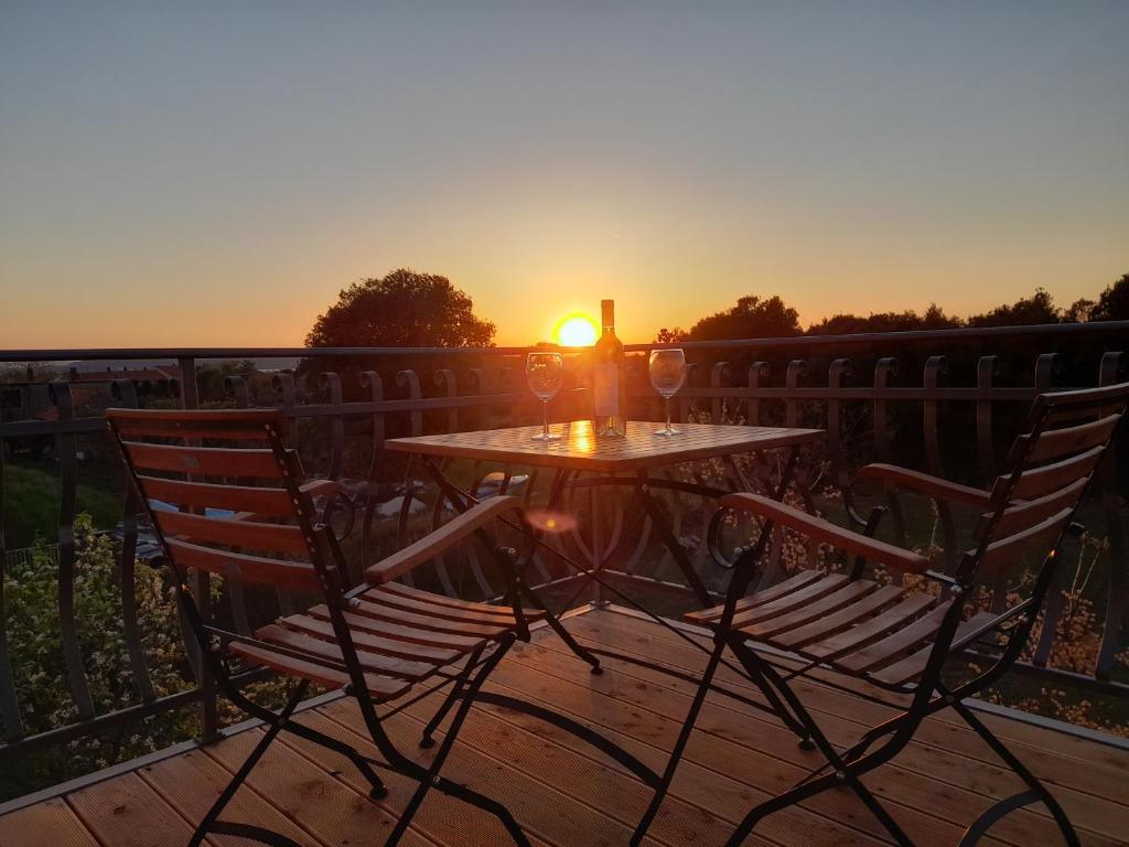 una mesa y sillas en una terraza con vistas a la puesta de sol en Ferienwohnung Marko, en Sukošan
