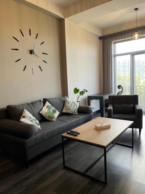 a living room with a couch and a clock on the wall at Monstera Leaf Appartment, Kechi House, Tsaghkadzor in Tsaghkadzor