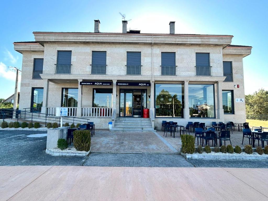 un edificio con mesas y sillas delante de él en HOSTAL RESTAURANTE AQUA, en Ourense