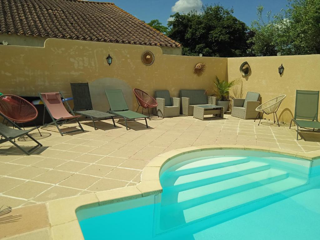 a patio with chairs and a swimming pool at les figuiers et les rosiers proche puy du fou in Saint-Germain-de-Prinçay