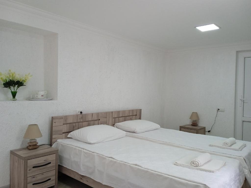 1 dormitorio con 2 camas, sábanas blancas y toallas en Elegant Hotel, en Kutaisi