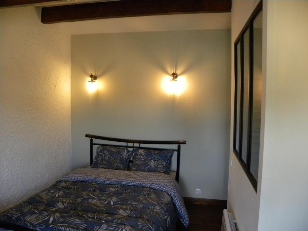 a bedroom with a bed and two lights on the wall at les figuiers et les rosiers proche puy du fou in Saint-Germain-de-Prinçay