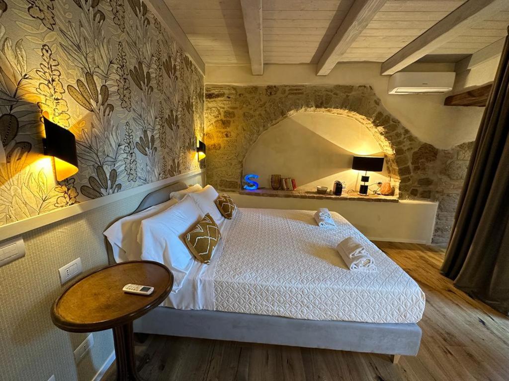 um quarto com uma cama, uma mesa e um espelho em La Bartolomea Home & Suite em Pitigliano