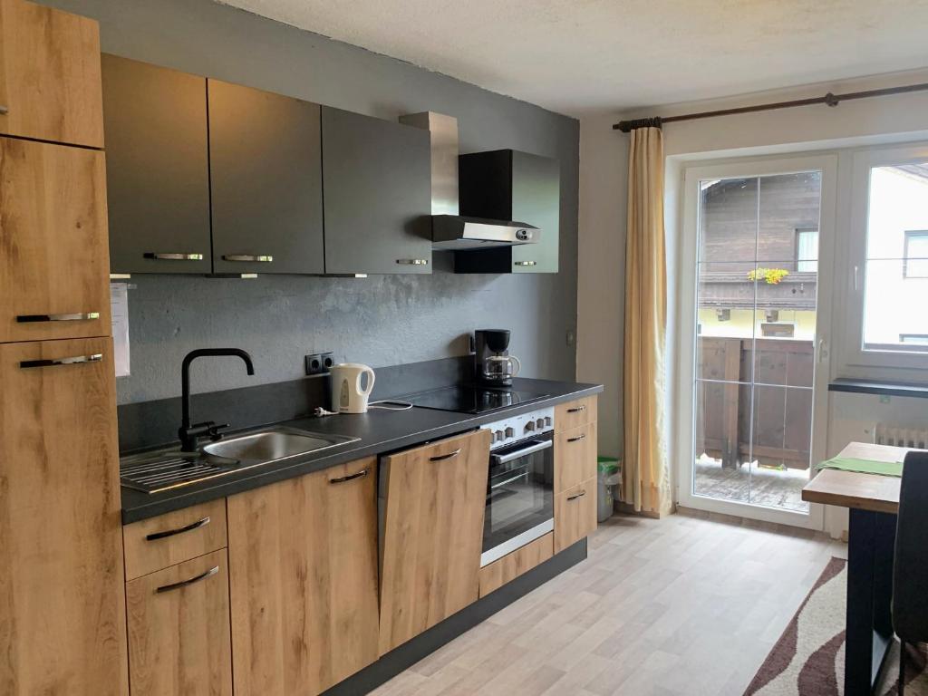 uma cozinha com armários de madeira, um lavatório e uma janela em Appartements Konrad em Söll