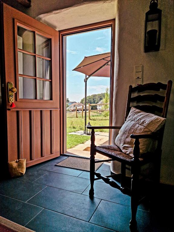 a porch with a chair and an open door with an umbrella at Ferienhaus "Entenhaus" im Gutshaus De La Fontaine in Feilsdorf