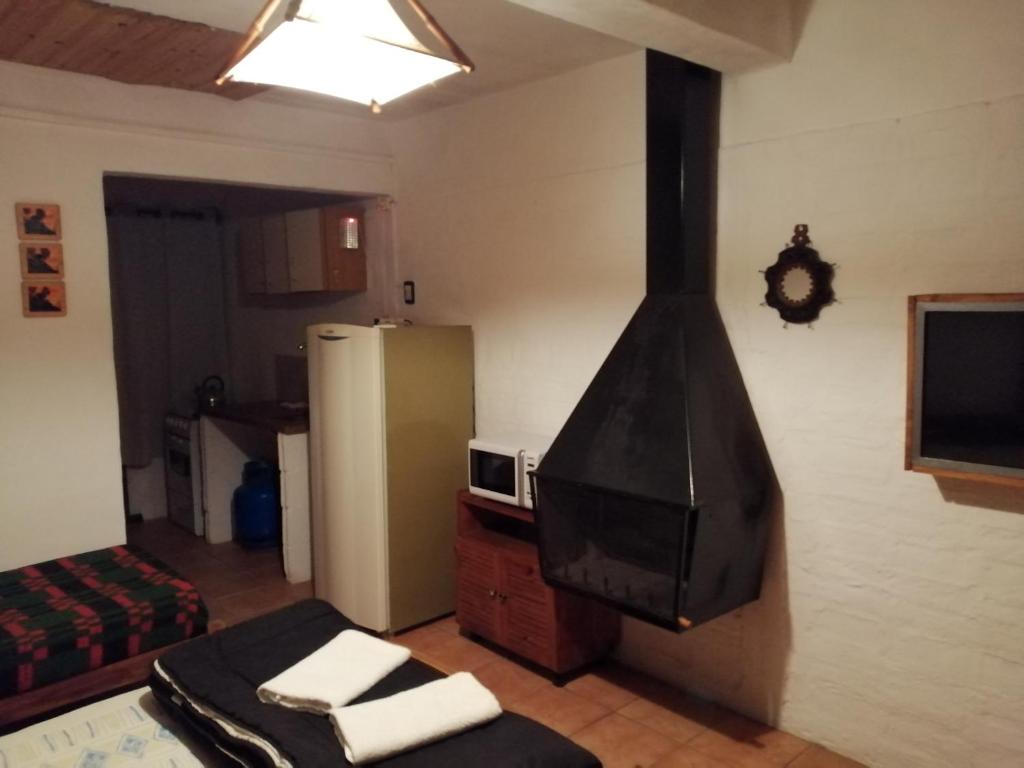 een woonkamer met een televisie en een koelkast bij Bungalows Atardecer Apart Hotel in Atlántida