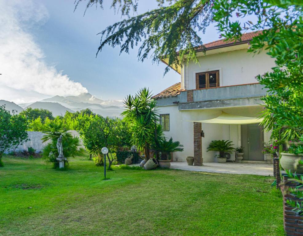 een huis met een groene tuin met een grasveld bij Villa Asia in Viagrande