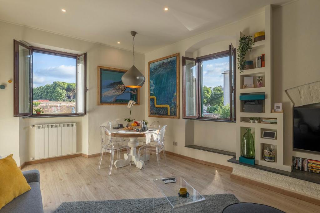 un soggiorno con tavolo, sedie e finestre di The Architect Suite - Canals View a Livorno