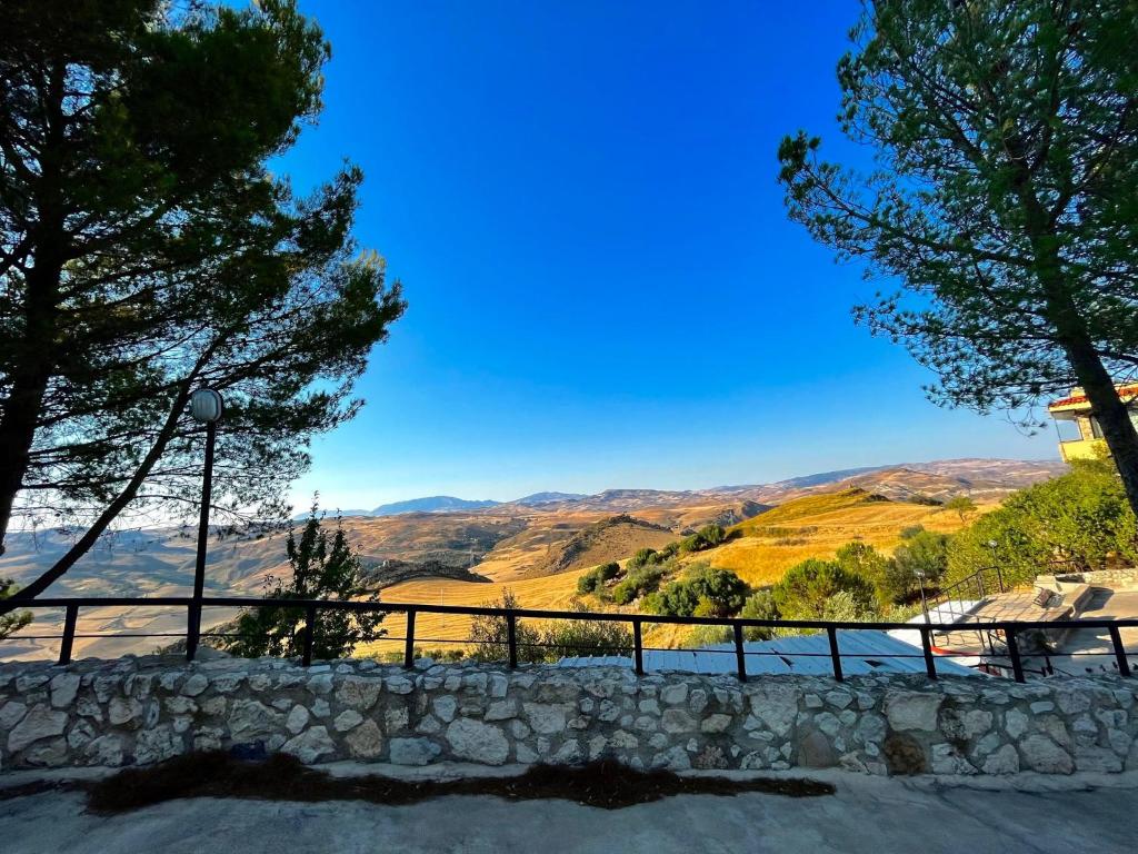a stone wall with trees and mountains in the background at Agriturismo Villa Assunta in Santa Caterina Villarmosa