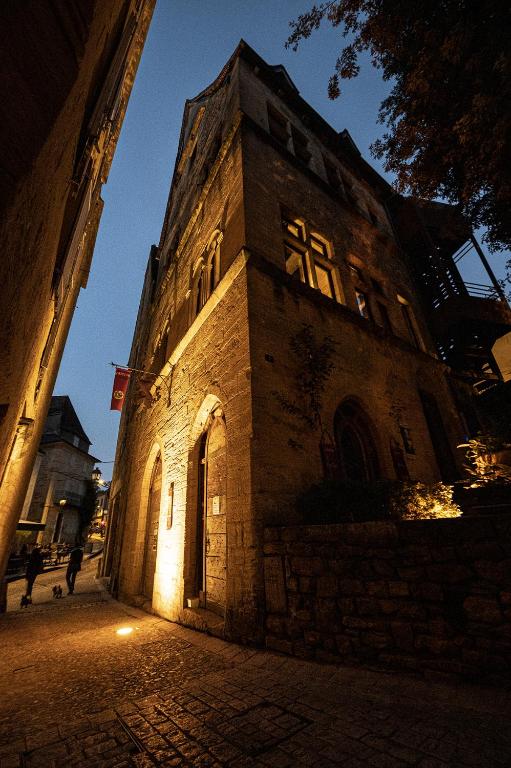un bâtiment avec une tour d'horloge dans une rue la nuit dans l'établissement Hôtel particulier Fénelon - XIIIe, à Sarlat-la-Canéda