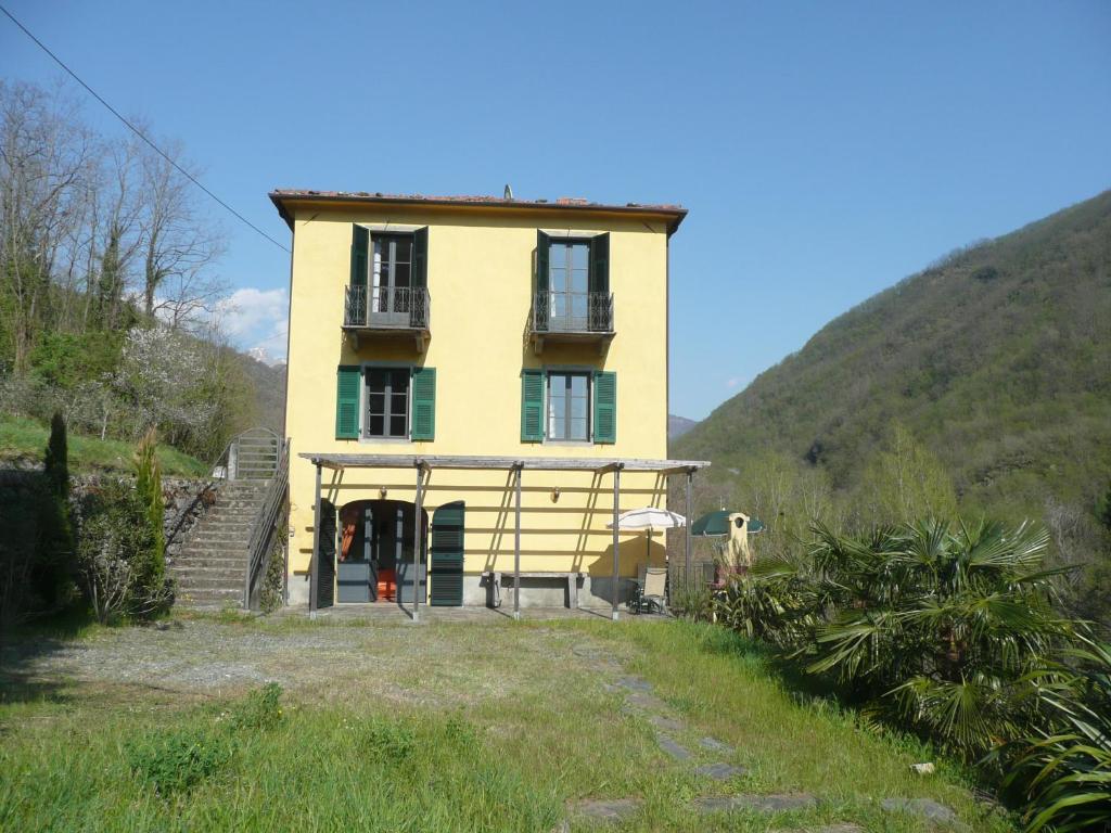 a yellow house with a hill in the background at Vila with private pool in Licciana Nardi