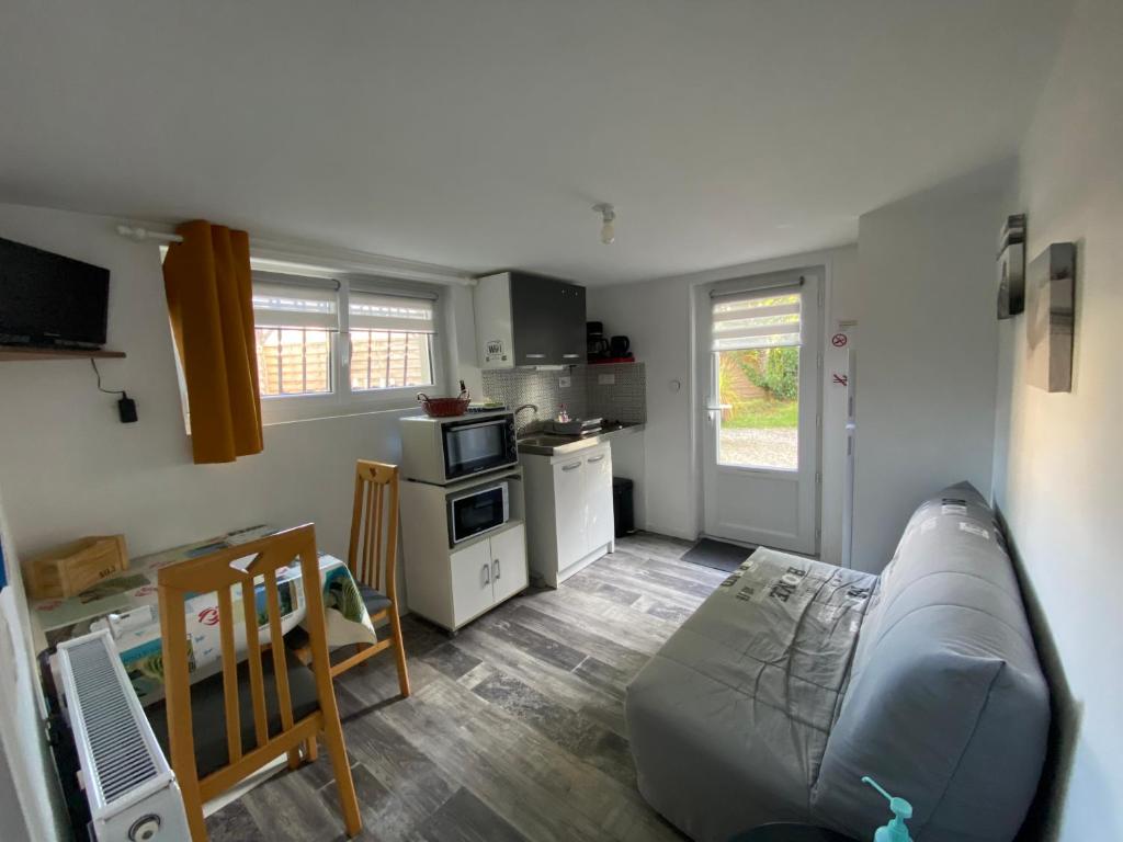 ein Wohnzimmer mit einem Sofa und einer Küche in der Unterkunft Le palmier in Saint-Georges-de-Pointindoux