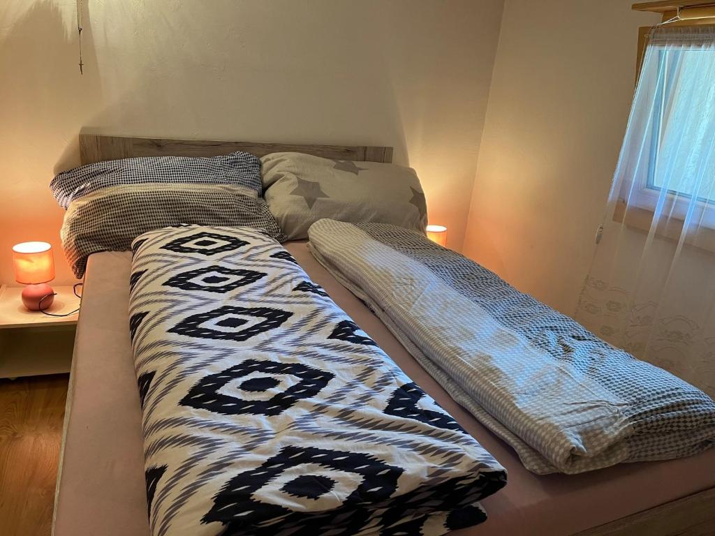 uma cama com dois edredões num quarto em Historische Maisonette-Wohnung mit Gästekarte und Ermässigungen em Naters