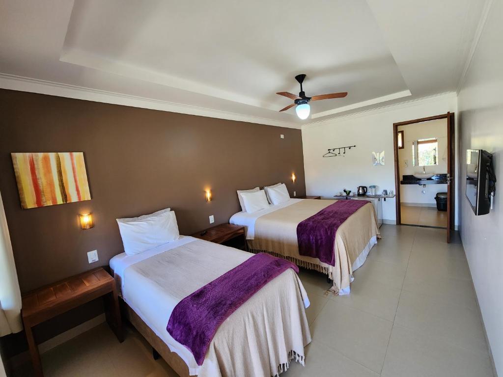 a hotel room with two beds and a ceiling fan at Pousada Camarás in Alto Paraíso de Goiás