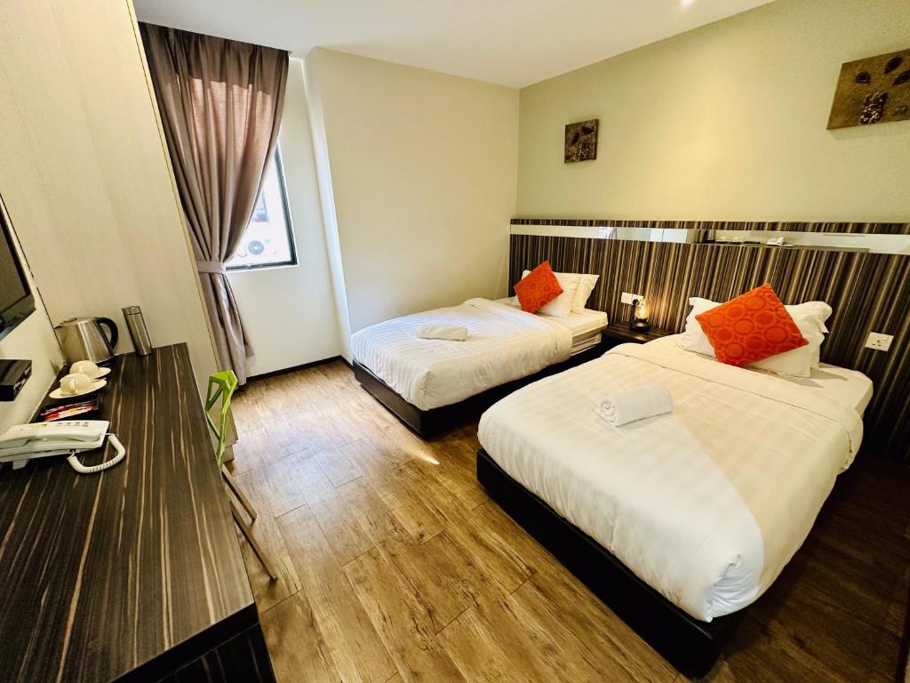 Habitación de hotel con 2 camas con almohadas de color naranja en Kino Hotel, en Shah Alam