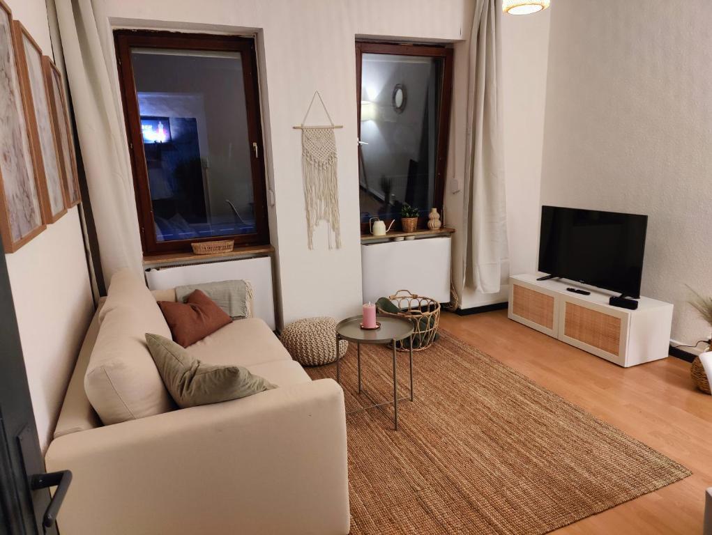 ein Wohnzimmer mit einem weißen Sofa und einem TV in der Unterkunft Bliss - 3 Zimmer, Boho, Arbeitsplatz, Netflix in Gießen