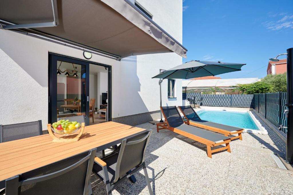een patio met een tafel en stoelen en een zwembad bij ZEN apartment in Trogir