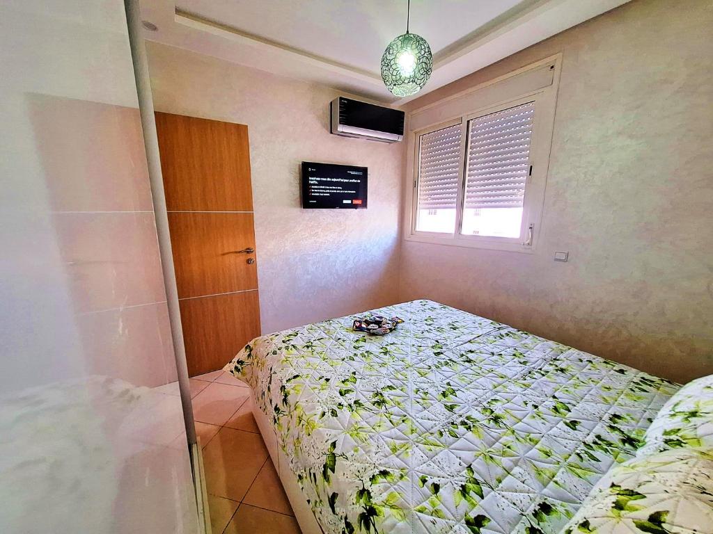 um pequeno quarto com uma cama e uma janela em great location flat Calm & Chocolat gift em Agadir