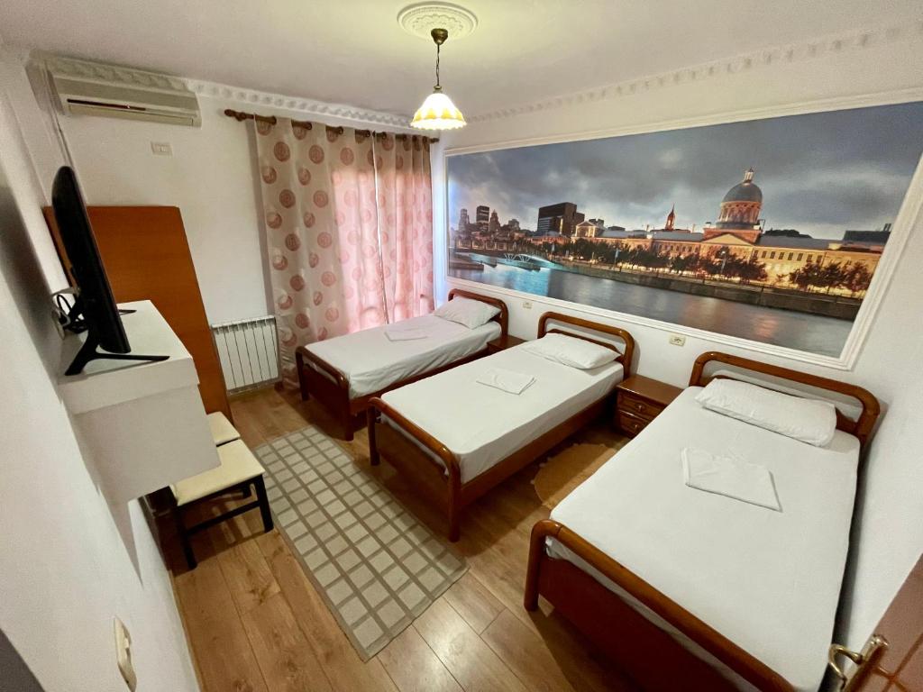 una habitación con 2 camas y una pintura de una ciudad en RAMIS Hotel & Outdoor Sports Center, en Përmet