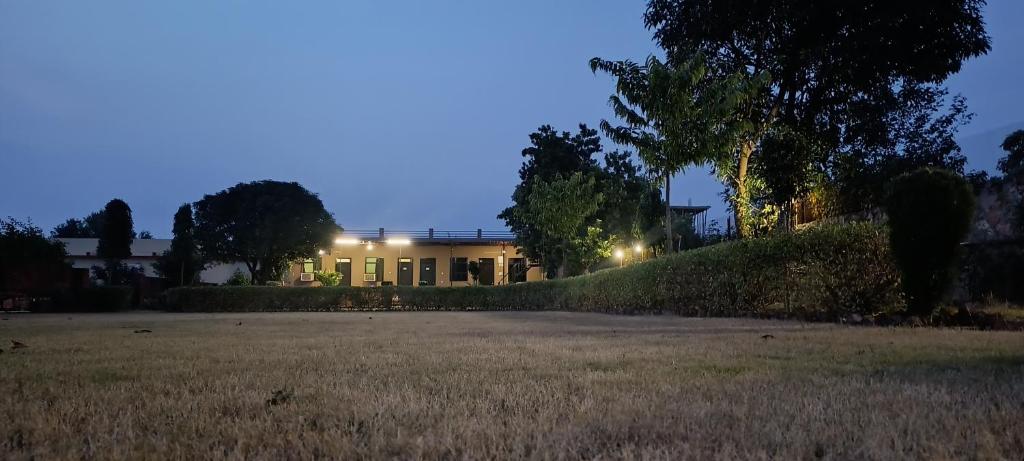 una casa con luces encendidas en un campo por la noche en Ranthambore Aravalli, en Sawāi Mādhopur