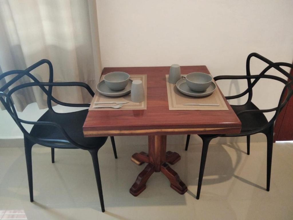 una mesa de madera con 2 sillas y 2 tazas. en Apartamento en Bacalar