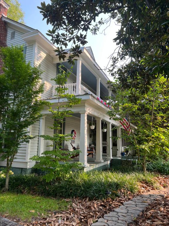 Maison blanche avec drapeau américain sur la terrasse couverte dans l'établissement Magnolia House & Gardens B&B, à Clover