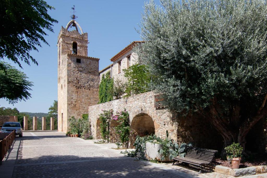 a building with a tower and a tree and a bench at Casa bascara in Báscara