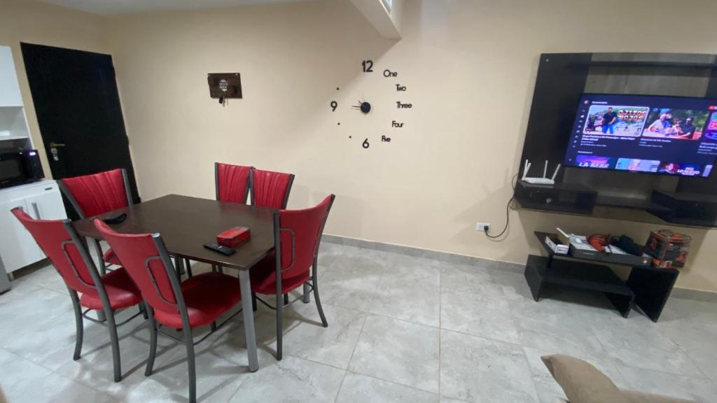 a dining room with a table and red chairs and a tv at Las Rejas Departamento in San Fernando del Valle de Catamarca