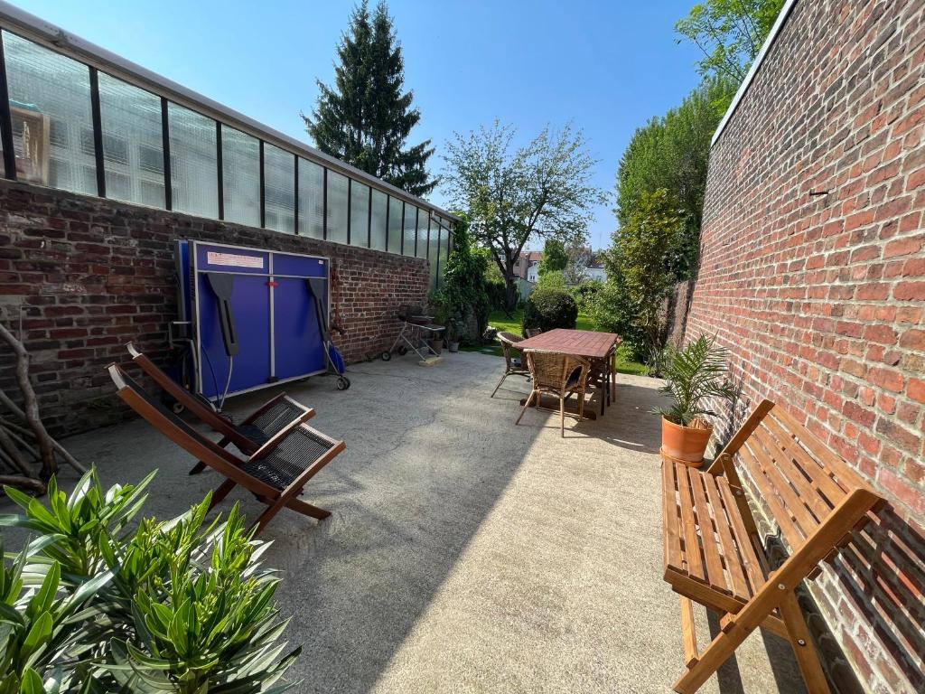 un patio avec des bancs et une table ainsi qu'un bâtiment dans l'établissement La chambre jaune maison avec grande terrasse et garage privé, à Lille