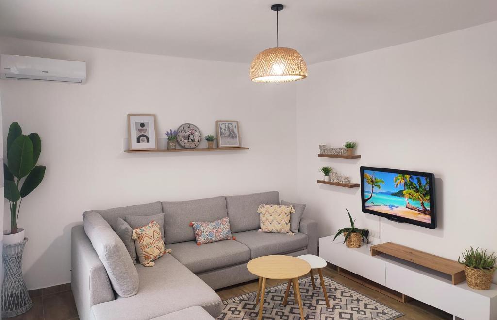 a living room with a couch and a tv at Saeri's Stylish Apartment in Shëngjin