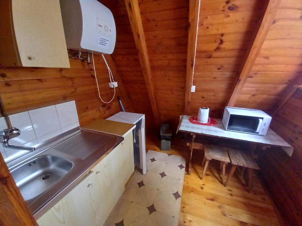 Il comprend une petite cuisine équipée d'un évier et d'un four micro-ondes. dans l'établissement Domki Letniskowe KORMORAN, à Kąty Rybackie