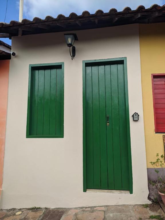 two green doors on the side of a house at Cantinho na Chi´apada II in Lençóis