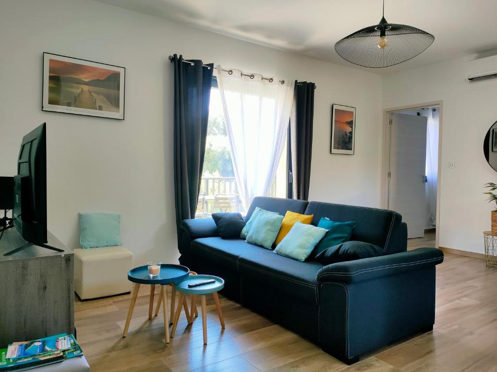 uma sala de estar com um sofá azul e uma televisão em Appartement neuf avec balcon et 2 chambres em Saint-Florent