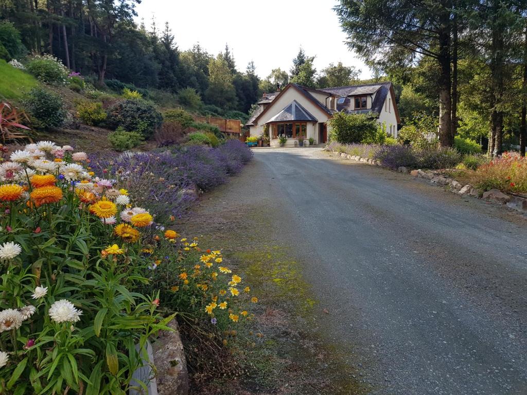 a house with flowers on the side of a road at FOREST VIEW Woodland lodge in Ballard
