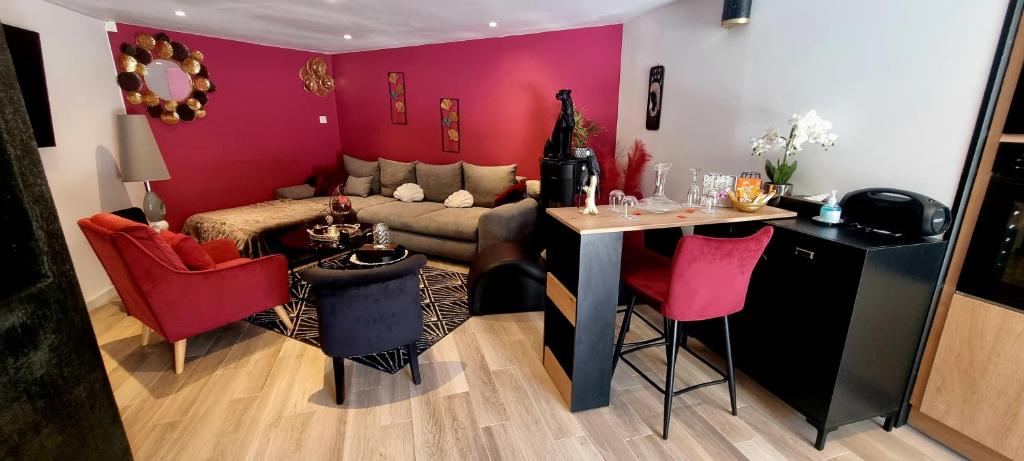 a living room with a couch and a table with red chairs at appartement cosy in Feigères