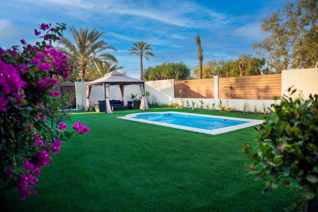 a yard with a swimming pool and a gazebo at Nordic Gardens in Manama