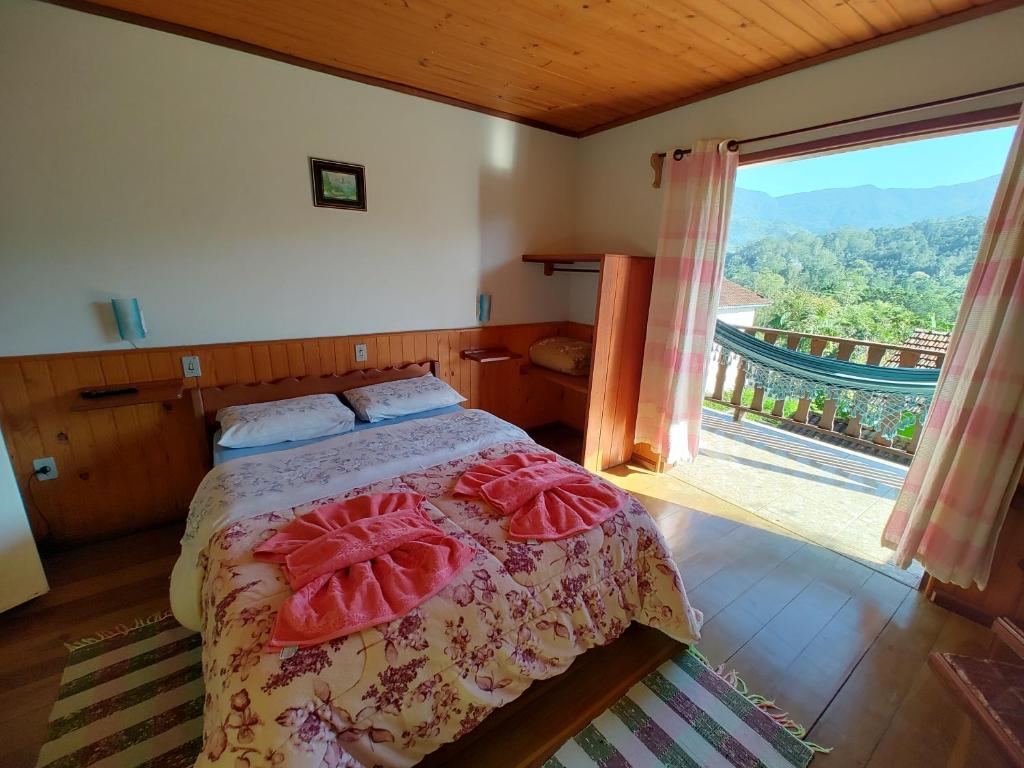 ein Schlafzimmer mit einem Bett und einem großen Fenster in der Unterkunft Pousada Solar das Flores in Visconde De Maua