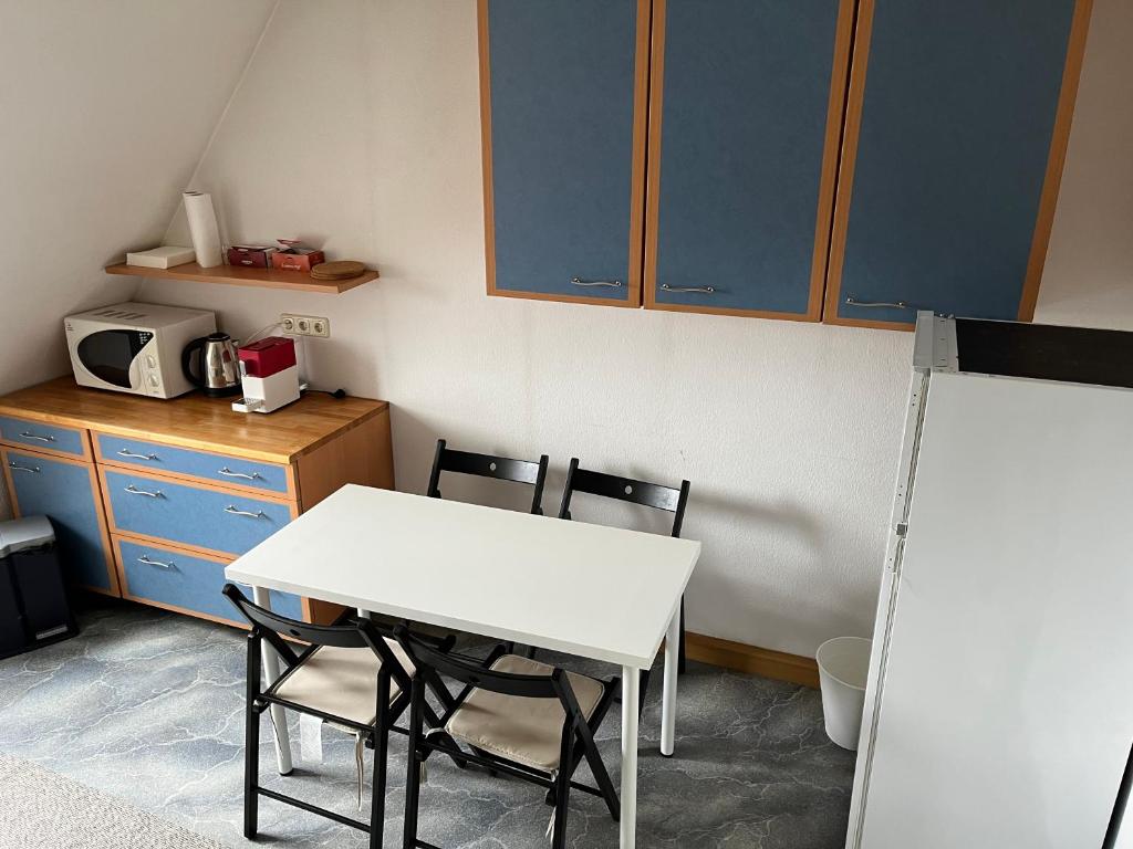 a kitchen with a white table and chairs and a microwave at Ferienwohnung / Monteurzimmer in Kitzingen