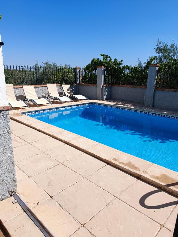 a swimming pool with loungers and chairs in front of a fence at La Laguna in Almedinilla